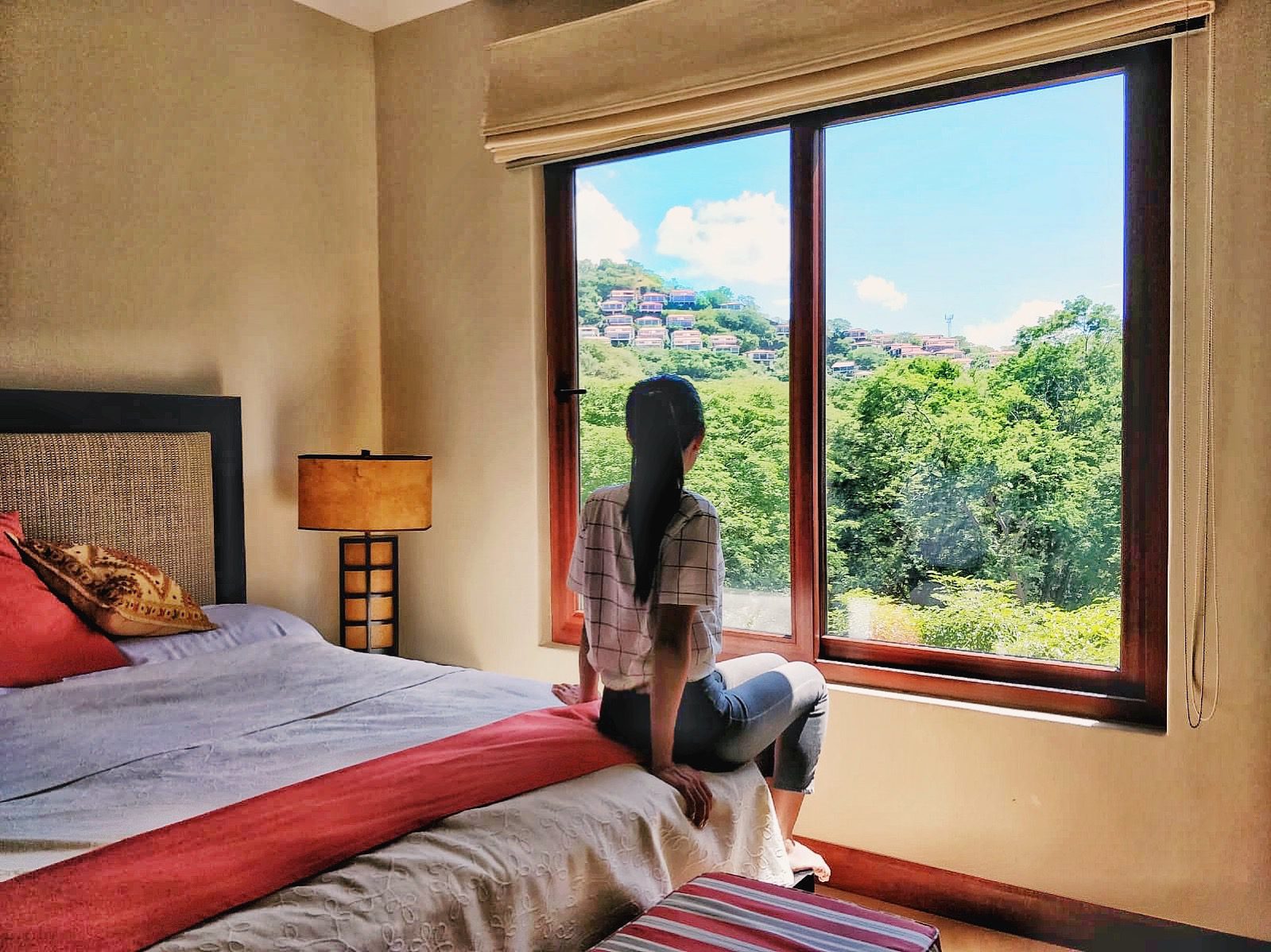 Woman looking out to the green forest from window in a Playa Hermosa Costa Rica Airbnb