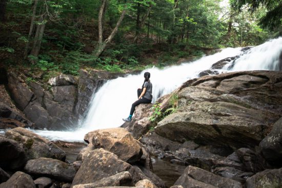 Woman sitting at the base of Skeleton Falls in Muskoka Ontario Canada