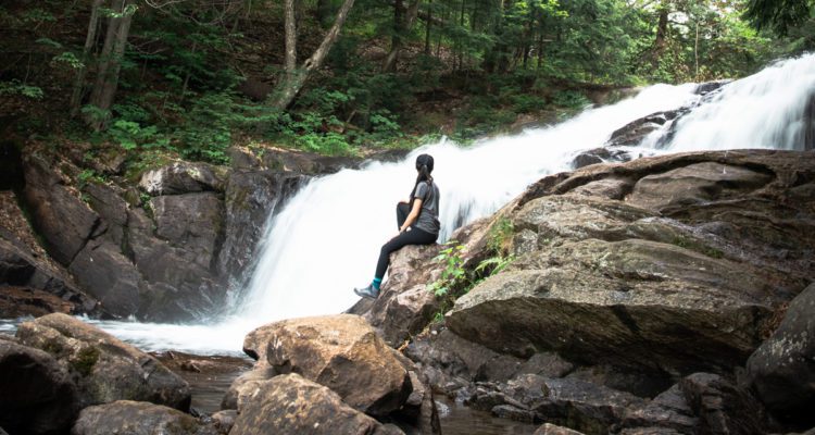 Woman sitting at the base of Skeleton Falls in Muskoka Ontario Canada