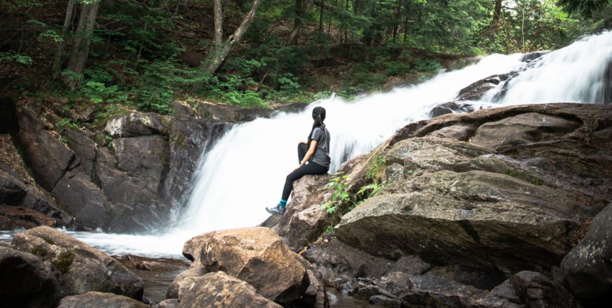 Woman sitting at the base of Skeleton Falls in Muskoka Ontario Canada